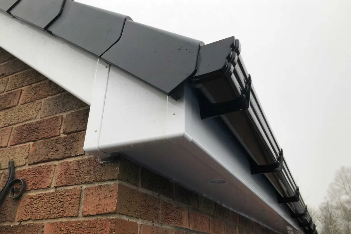 A new white fascia and soffit box end with black guttering on brickwork