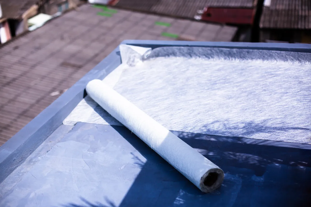 A roll of fibreglass matting set out on a primed GRP roof deck
