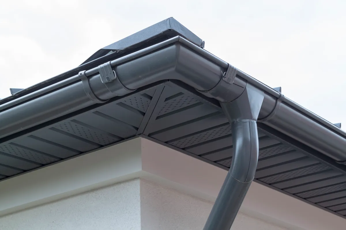 A new gutter and downpipe run at the eaves