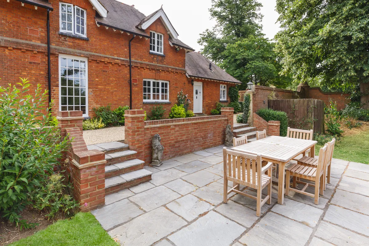 A sandstone patio and steps behind a red brick house