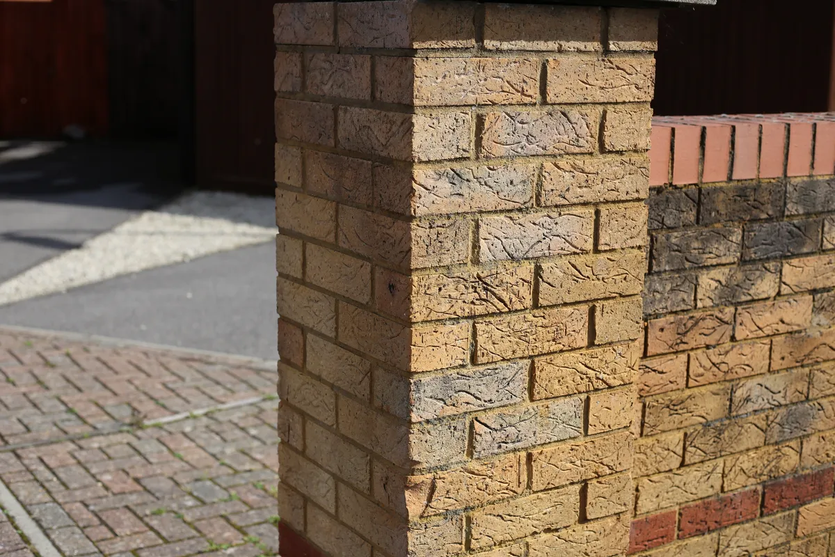 A brick boundary wall and piers running along a driveway