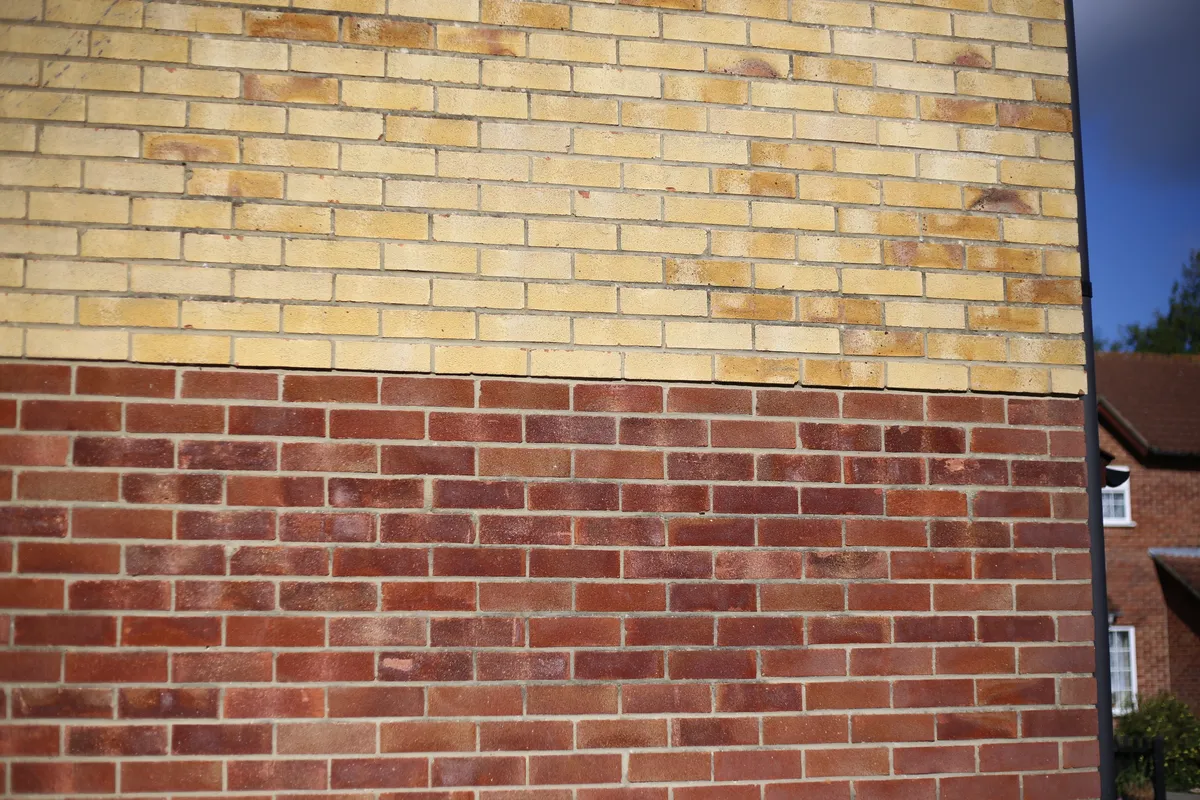 A brick boundary wall built up to a timber fence